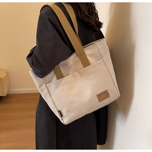 Detail of canvas tote bag showing textured beige fabric and olive green woven strap