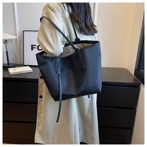 Sac fourre-tout noir minimaliste porté à l'épaule par un mannequin pour le travail