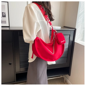 Détail du sac bandoulière rouge en toile avec chaîne argentée et mini pochette amovible