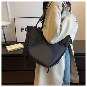 Grand sac fourre-tout noir minimaliste porté avec un trench beige pour un style bureau chic