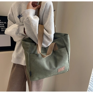 Detail of army green canvas tote bag with brown straps and stylish leather logo patch