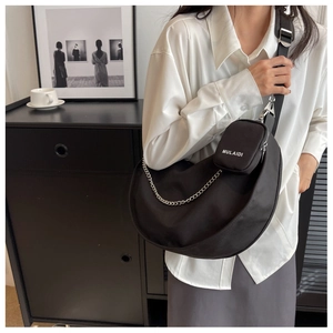 Détail d'un sac bandoulière croissant noir avec chaîne argentée et pochette amovible