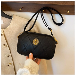 Détail du sac bandoulière matelassé noir avec emblème d'ours doré et texture en cuir