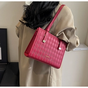 Detailed view of red quilted tote bag with gold hardware worn on model shoulder