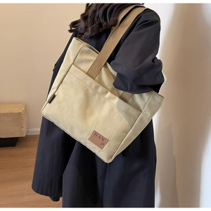 Detail of high-density canvas tote bag showing wide outer pocket and premium leather logo