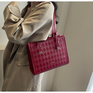 Detailed view of the red quilted leather tote bag with elegant gold logo and shoulder strap
