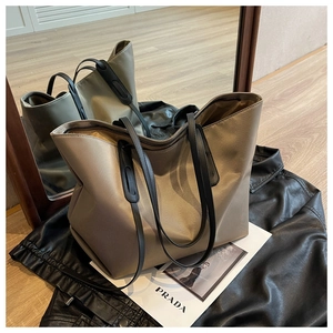 Détail d'un sac cabas en tissu Oxford kaki avec des lanières en cuir noir sur du cuir sombre
