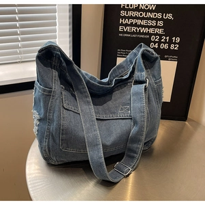 Dettaglio della borsa tote in denim lavato con cuciture bianche a contrasto e strappi