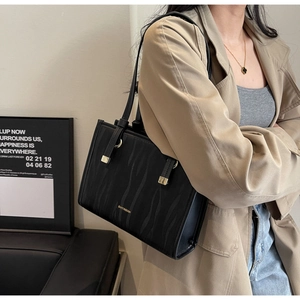 Detailed close-up of a black tiger pattern tote bag with gold logo and leather strap