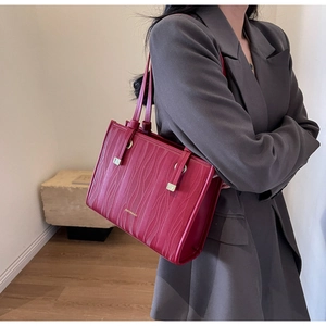 Detail of red bridal handbag with wave pattern texture and gold hardware on suit model