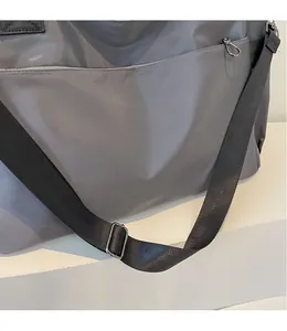 Détail de la bandoulière longue réglable et de la boucle métallique sur le sac gris