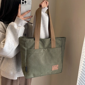 Olive green canvas tote bag with brown straps and leather logo for women's daily commute