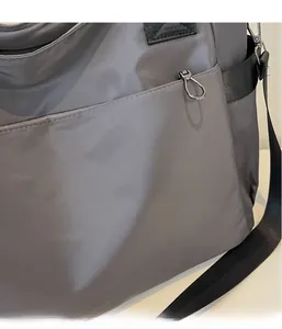 Détail du sac de voyage Oxford gris montrant le tissu durable et la fermeture éclair en métal
