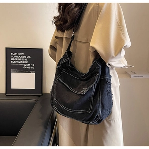 Dettaglio borsa in denim nero con cuciture a contrasto bianche e tracolla regolabile