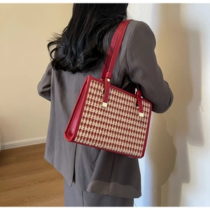 Detail of red houndstooth tote bag with premium leather straps on model's shoulder