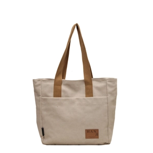 Minimalist off-white canvas tote bag with brown straps and spacious front pocket