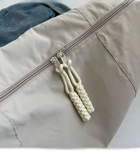 Detail view of the smooth double-zipper with sturdy woven cord pulls on the nylon bag