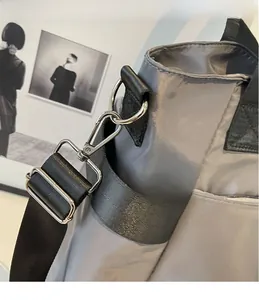 Détail du sac de voyage en nylon gris avec crochets en métal et bandoulière tissée noire