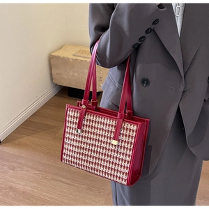 Detail of red houndstooth tote bag with leather handles and gold hardware accents