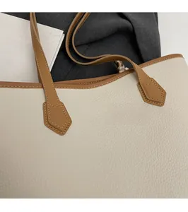 Close-up of V-shaped reinforced stitching on cream lychee leather tote bag strap