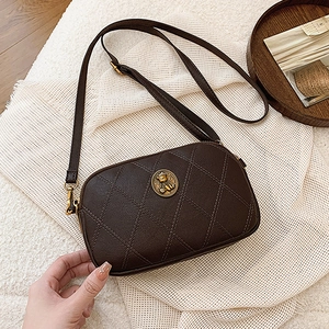 Petit sac bandoulière matelassé marron foncé avec logo doré sur fond de style de vie