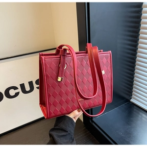 Close-up of red quilted leather wedding tote bag with elegant golden brand logo detail