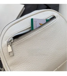 Detail of white lychee pattern leather crossbody bag with front zipper pocket and silver hardware