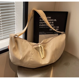 Close-up of cream nylon dumpling bag featuring woven zipper pull and woven shoulder strap