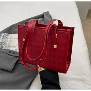 Detail of dark red tote bag with diamond lattice texture and golden hardware accents