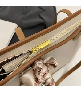 Detail of gold metal zipper and lychee grain leather on vintage tote bag with silk scarf