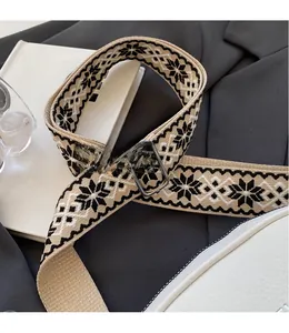 Detail of wide woven shoulder strap with geometric snowflake pattern and metal buckle