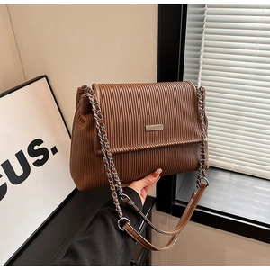 Detail of a brown tote bag featuring vertical pleated textures and silver chain strap
