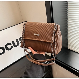 Close-up of brown corduroy shoulder bag showing vertical texture and silver metal buckle