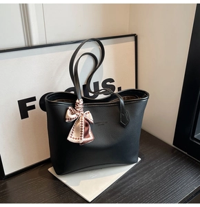 Detail of black pebbled leather tote bag with elegant checkered silk scarf handle