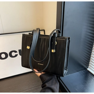 Close-up of black tote bag featuring wave texture finish and golden hardware detail