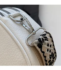 Close-up of silver metal hook and black-and-white jacquard wide strap on white leather bag