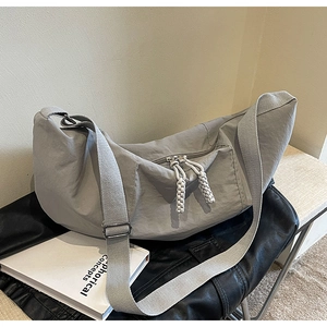 Detail of grey nylon crescent bag showing the woven rope zipper pull and wide strap
