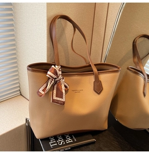 Detail of beige lychee pattern tote bag with brown straps and decorative scarf accessory