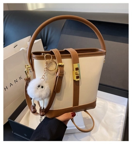 Detail of two-tone bucket bag with gold twist lock and plush monster charm