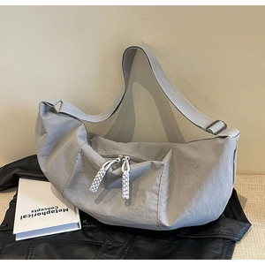 Close-up of grey nylon crescent bag with wide strap and double white braided zipper pulls