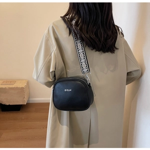 Detail view of black pebble leather crossbody bag with wide geometric woven strap