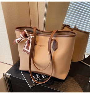 Detail of khaki pebbled leather tote with brown trim and decorative silk scarf on handle