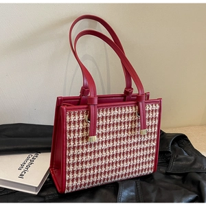 Detail of red leather and houndstooth tote bag featuring elegant golden hardware