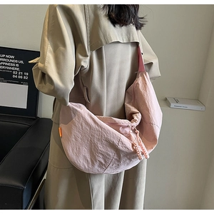 Detail view of the pink nylon dumpling bag showing fabric texture and orange tag
