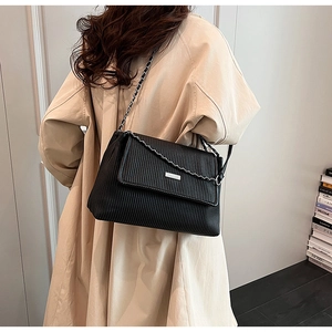 Detail of black pleated tote bag showing vertical texture and silver chain strap