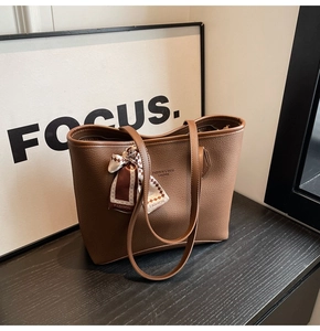 Detail of dark brown tote bag with lychee texture and decorative silk scarf
