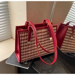 Detail view of red houndstooth tote bag with leather trim on a scene background