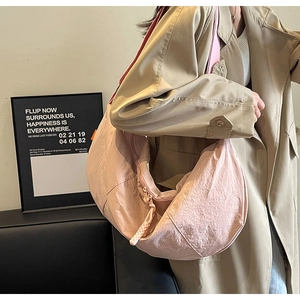 Detailed texture of pink nylon crescent bag with orange label and braided zipper puller