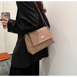 Brown pleated leather tote bag with silver metal bar and chain strap shown on model