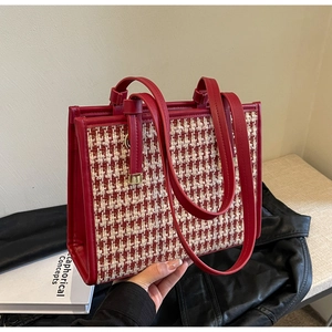 Detail of red houndstooth tweed tote bag with leather handles and gold metal hardware